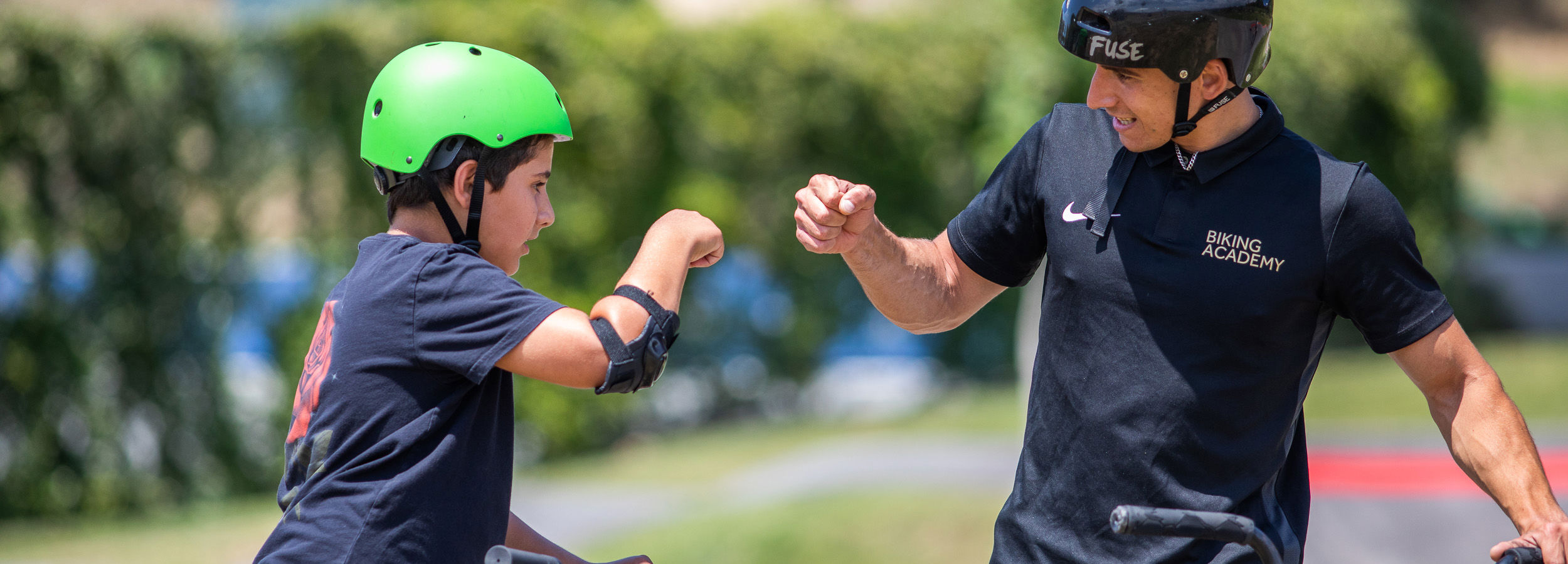 Mann und Mädchen geben sich die Faust, während sie sich an ihren Fahrrädern festhalten