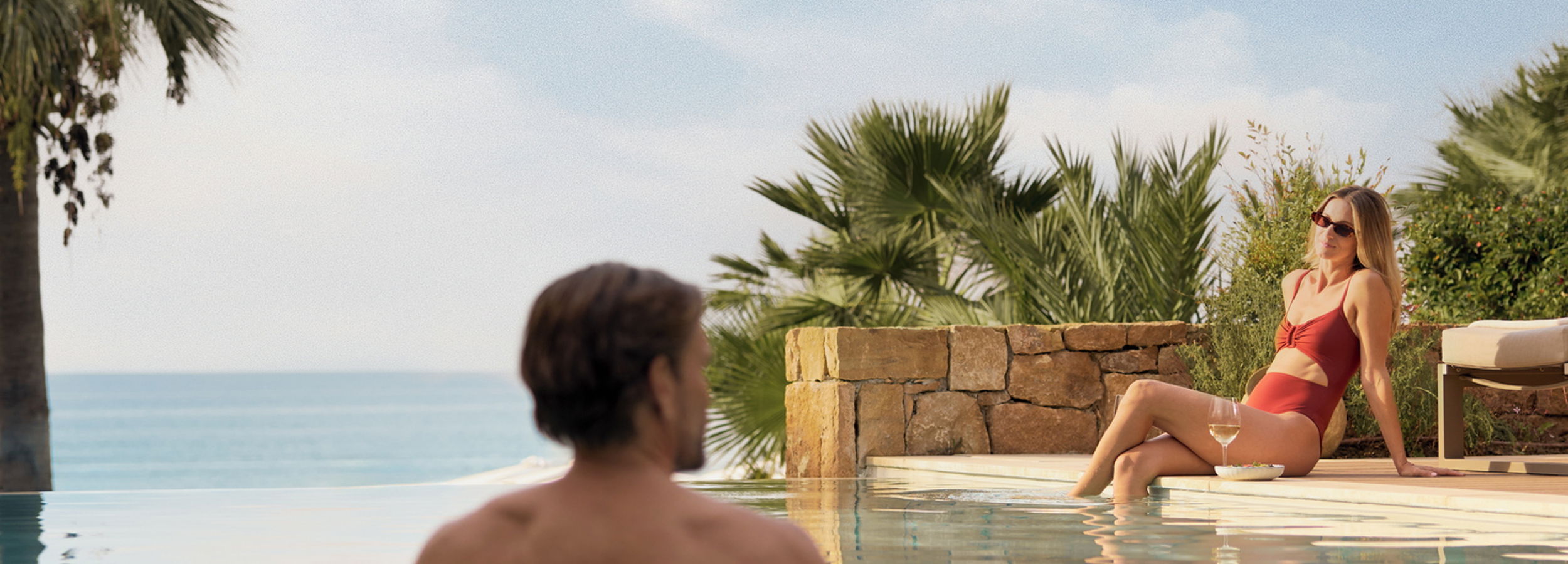 Man walking around the Sani Dunes heated pool with a view of resort