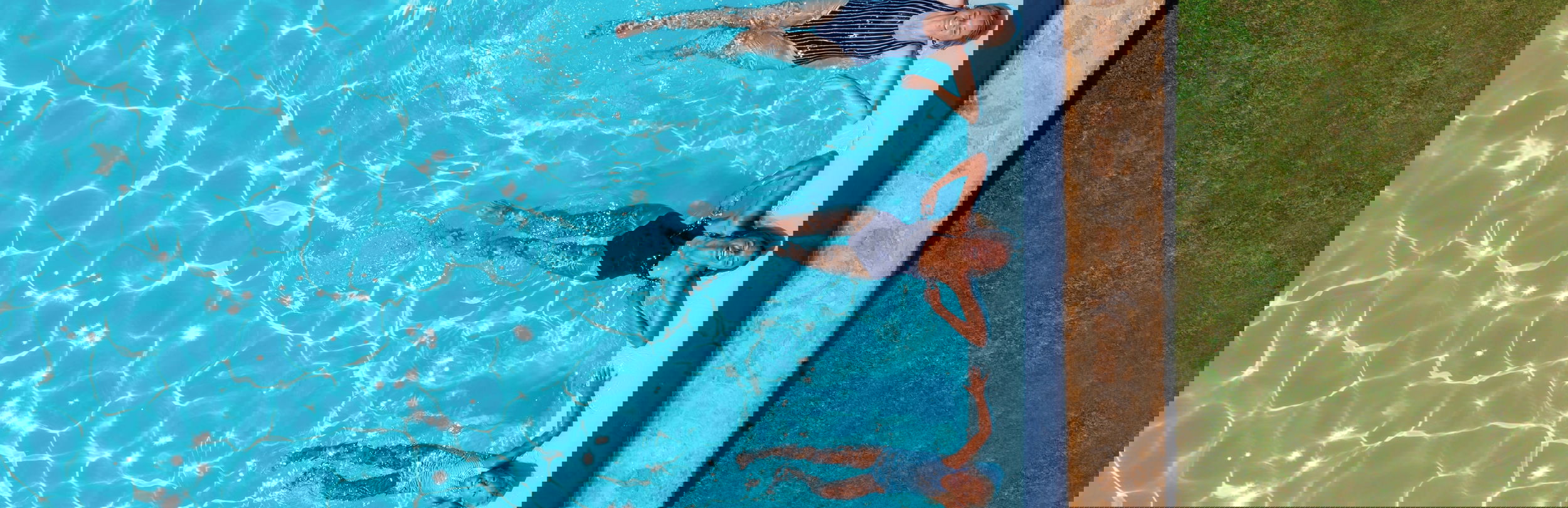 Coppia in piscina con la figlia sul deck accanto al piatto di frutta