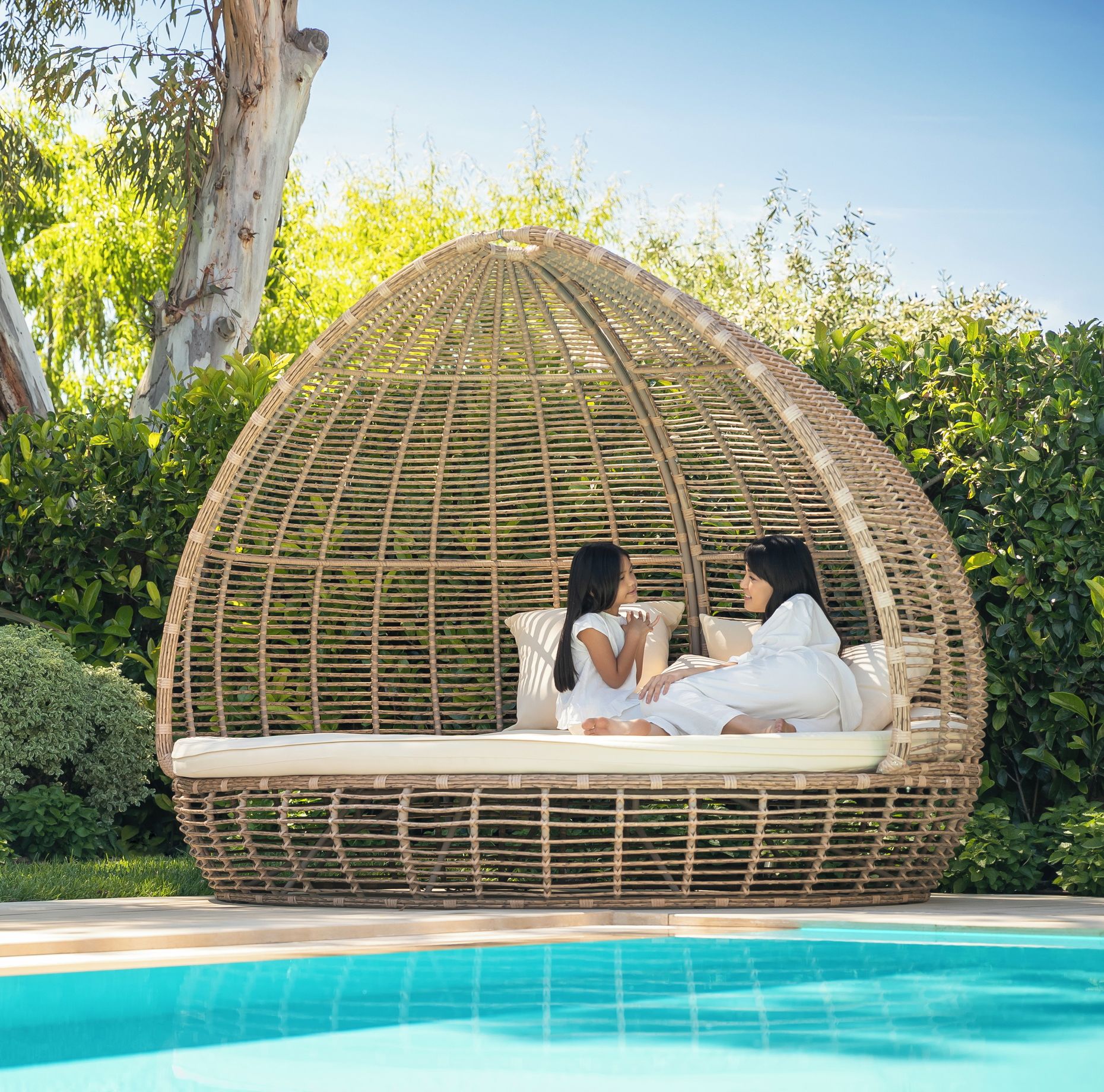 Mutter und Tochter im großen Korbstuhl neben dem Pool