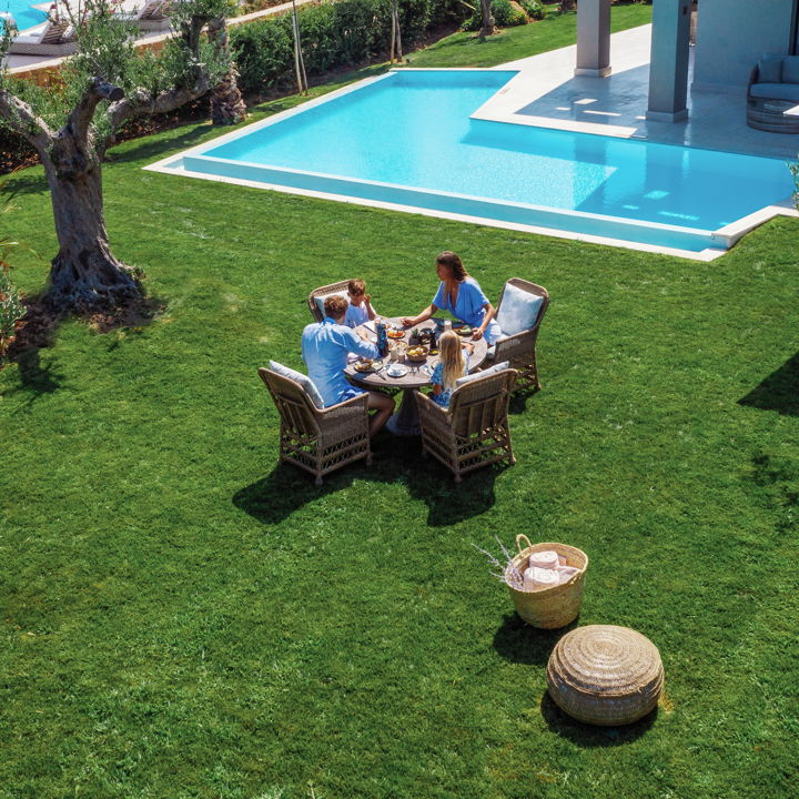 Familie beim Frühstück im privaten Garten neben dem Pool