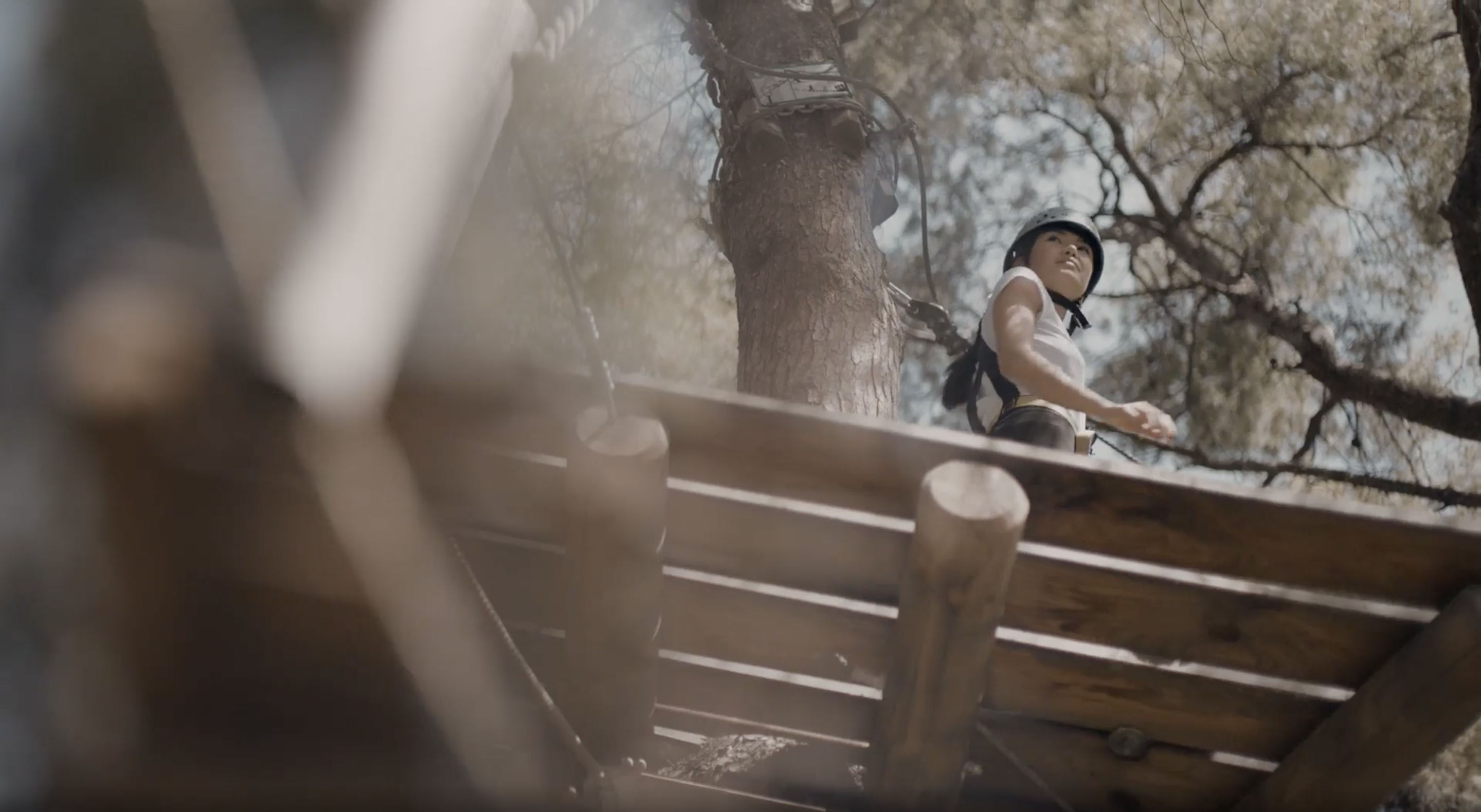Frau, die im Hochseilgarten in einer Baumkrone klettert
