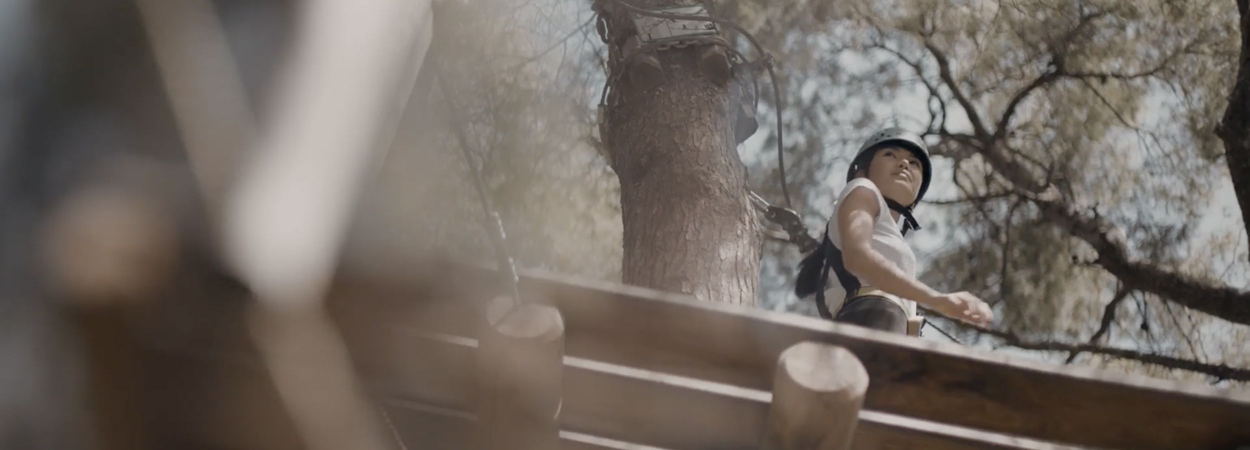 Frau, die im Hochseilgarten in einer Baumkrone klettert