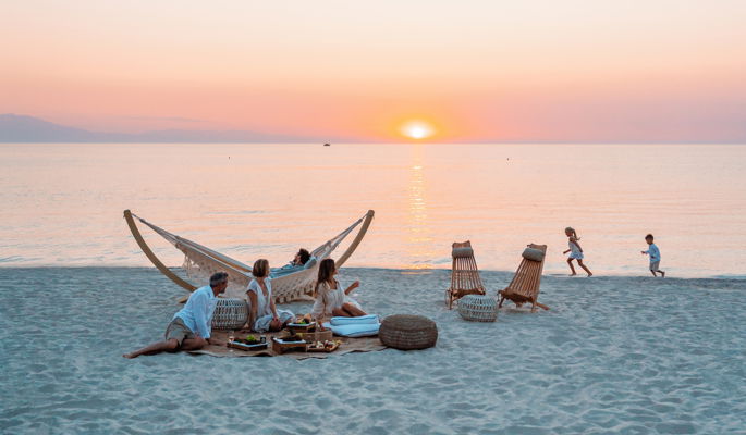 Famille sur la plage du Sani Resort au coucher du soleil