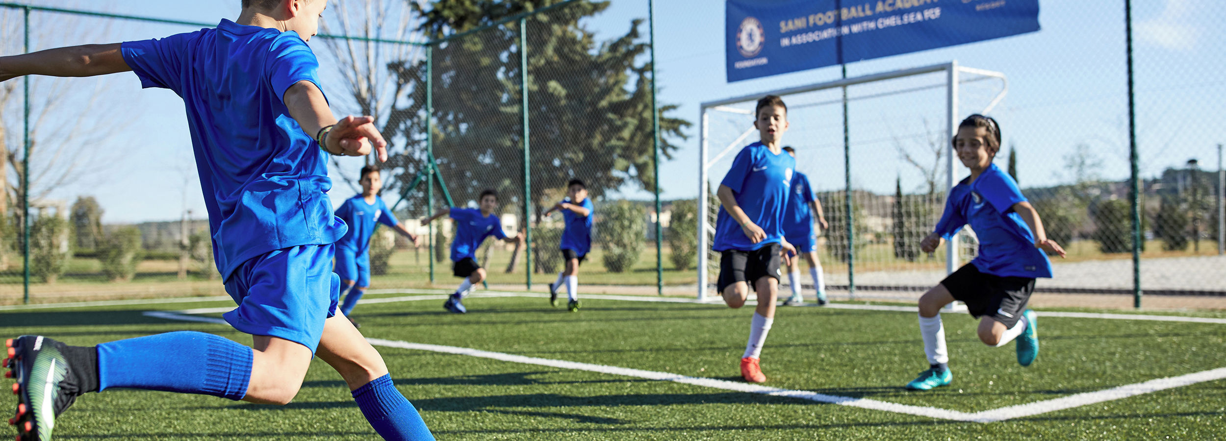 Junge, der in der Football Academy einen Fußball schießt