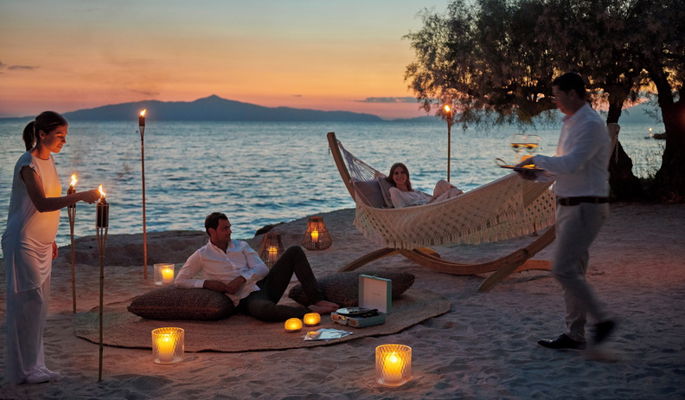Amis en train de dîner sur la plage au coucher du soleil