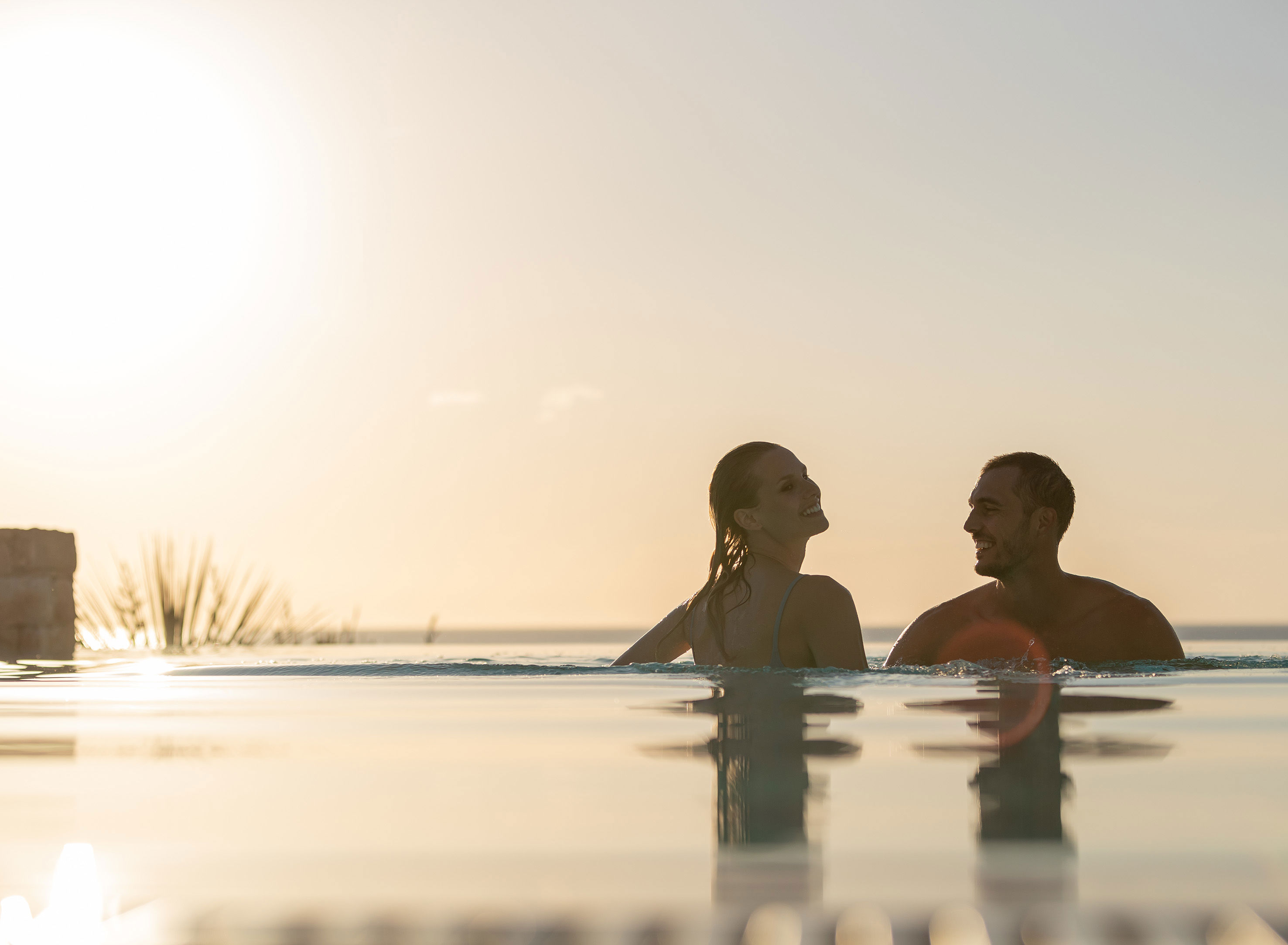 Coppia in piscina a sfioro al tramonto