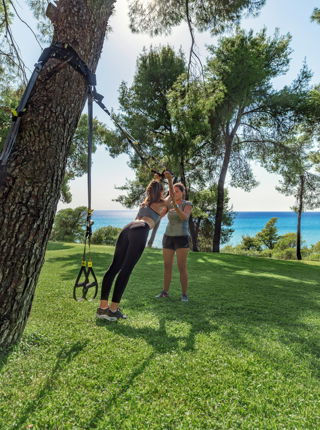 Femme s'étirant à l'aide de bandes attachées à un tronc d'arbre