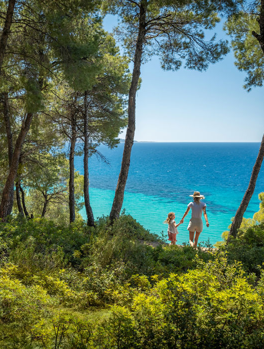 Mother and daughter walking from the forest towards the beach