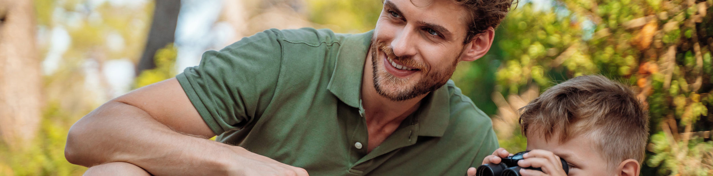 Vater und Sohn halten ein Fernglas im Sani Forest