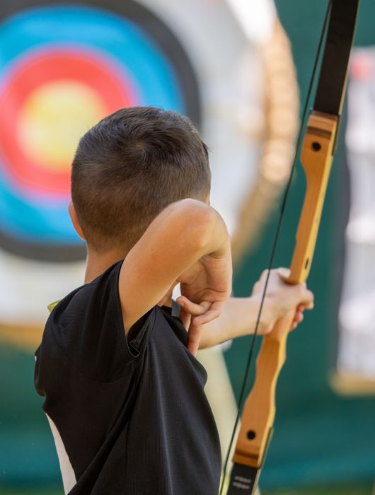 Мужчина направляет стрелу в цель на занятиях стрельбой из лука