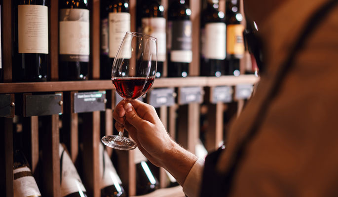 Mann schwenkt ein Glas Rotwein bei Weinprobe