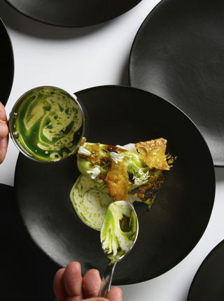 Chef pouring dressing on Simon Rogan Dish