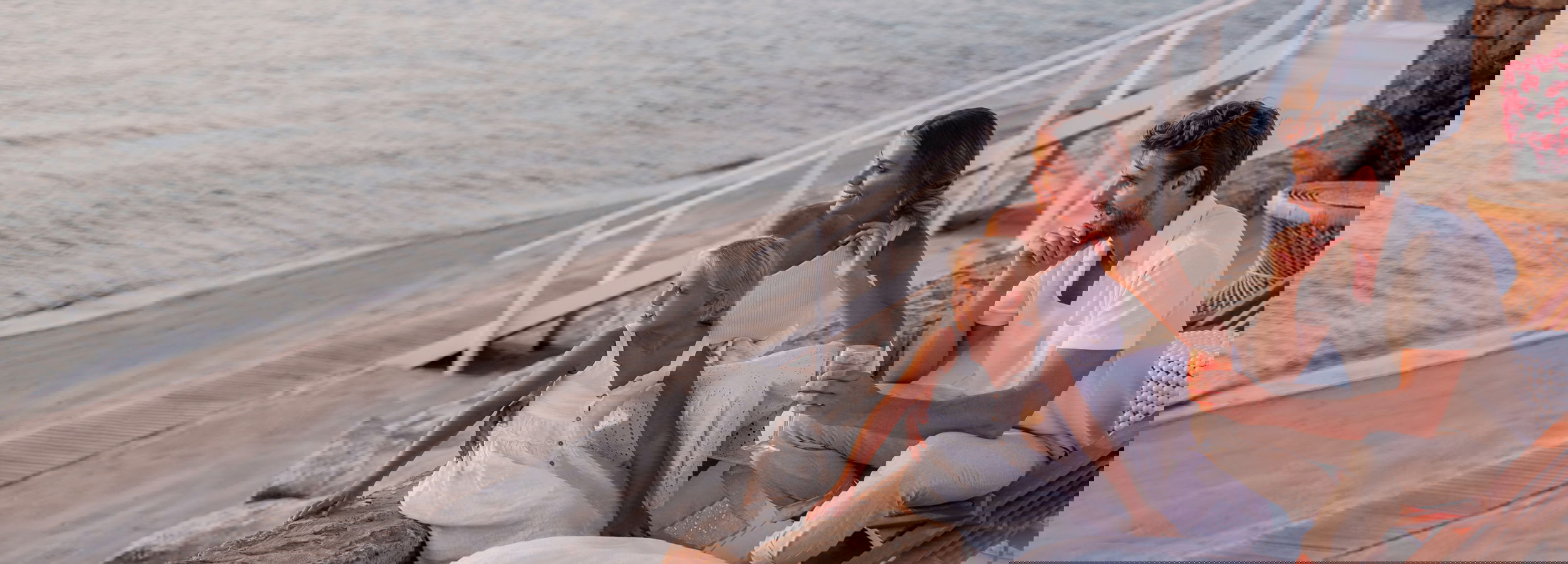 Famiglia seduta in riva al mare al tramonto