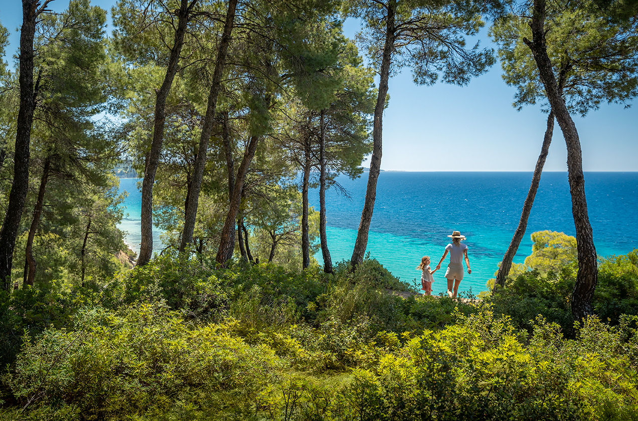 Mother and daughter walking from the forest towards the beach