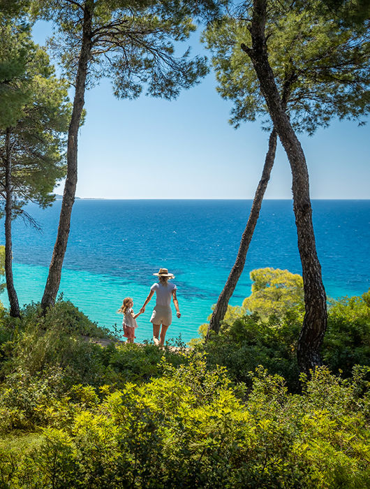 Mother and daughter walking from the forest towards the beach