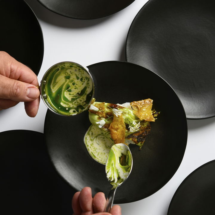 Chef pouring dressing on Plat Simon Rogan
