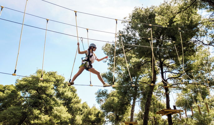 Ragazza sul percorso delle funi tra le cime degli alberi